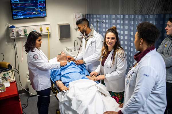 Four students work with a simulated patient in the simulation center.