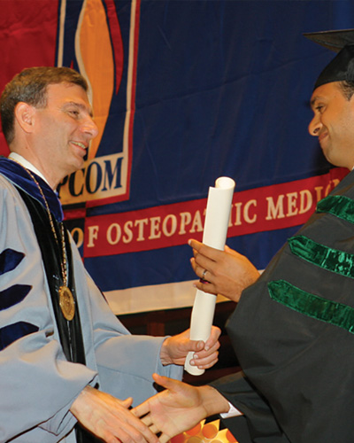 Dr. Schure distributes diplomas during a commencement ceremony