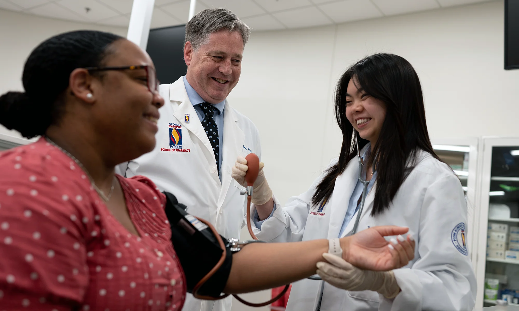 Doctor of Pharmacy students and faculty smiling during a hands-on learning exercise in a lab at PCOM Georgia