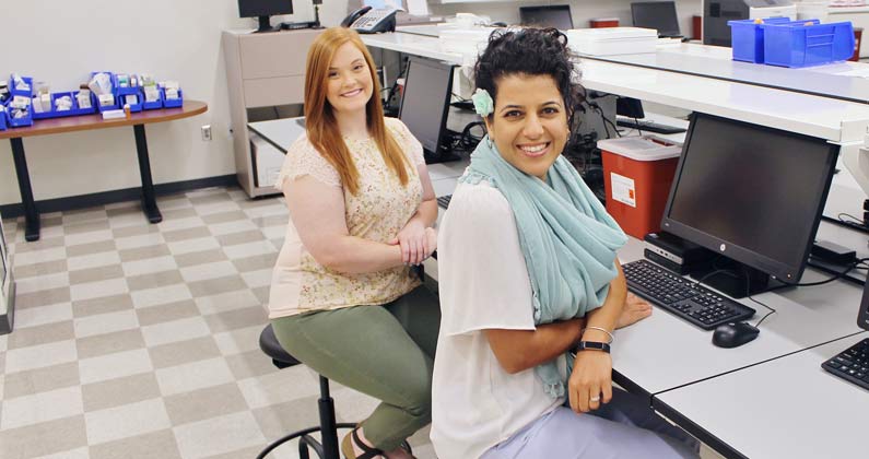 Lauren Avery, PharmD ‘18, and Irandokht Khaki, PharmD ‘18, pose within one of GA-PCOM's pharmacy practice teaching laboratories.