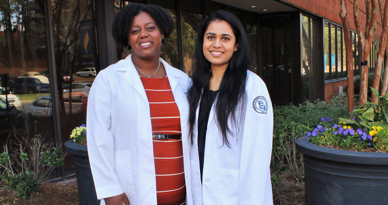 Ashruta Patel (DO '18) poses and smiles with faculty member Valerie Cadet, PhD, outside of PCOM Georgia's front doors
