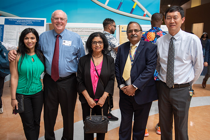 Faculty and guests smile in the PCOM Georgia atrium during Research Day