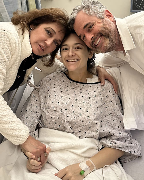 Angela in a hospital bed surrounded by her parents