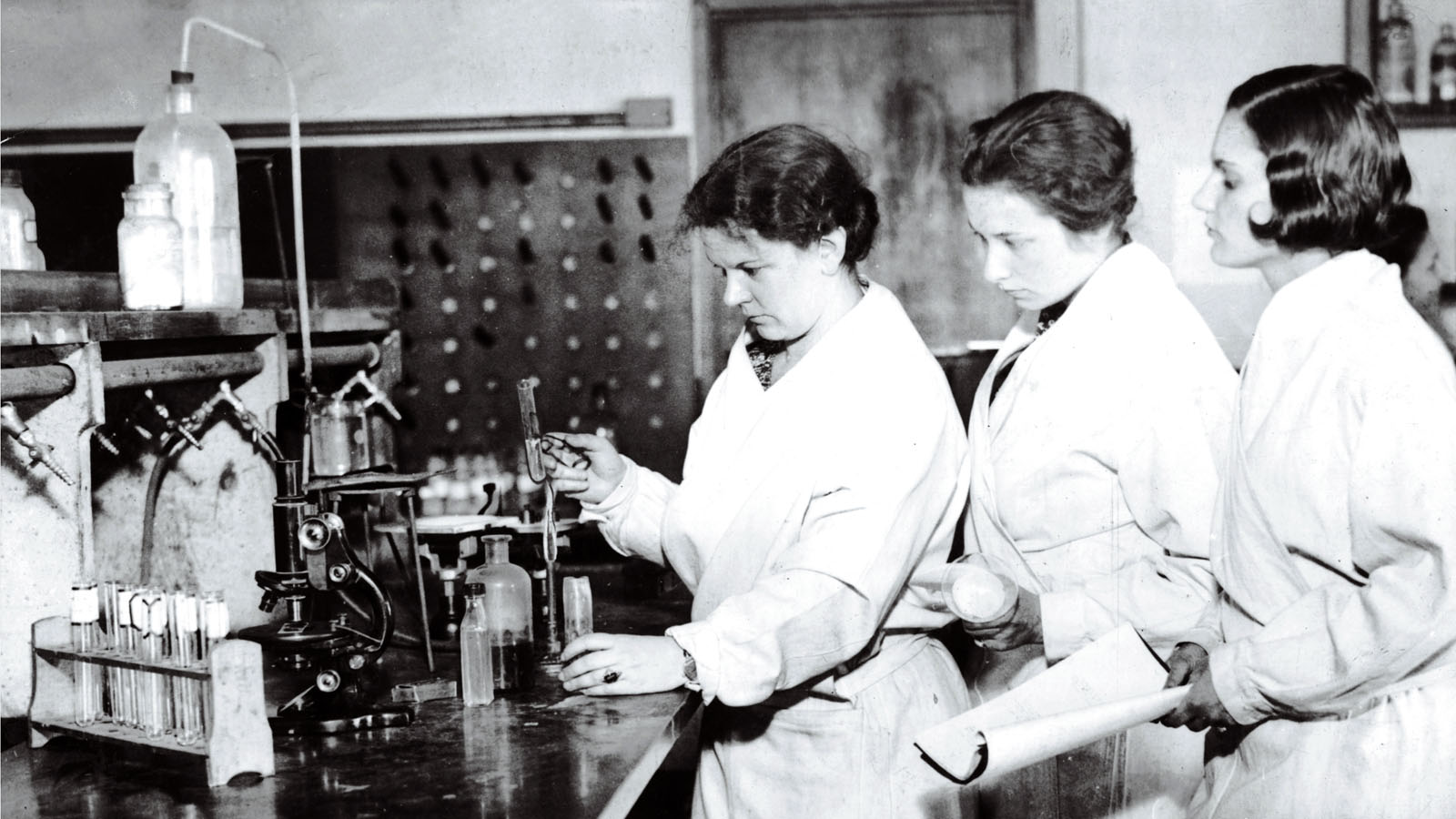 Female medical students looking at instruments in an old PCOM laboratory
