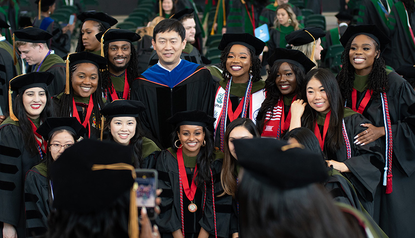 Dr. Wang smiles with members of the PCOM Georgia Doctor of Pharmacy Class of 2021 during commencement.