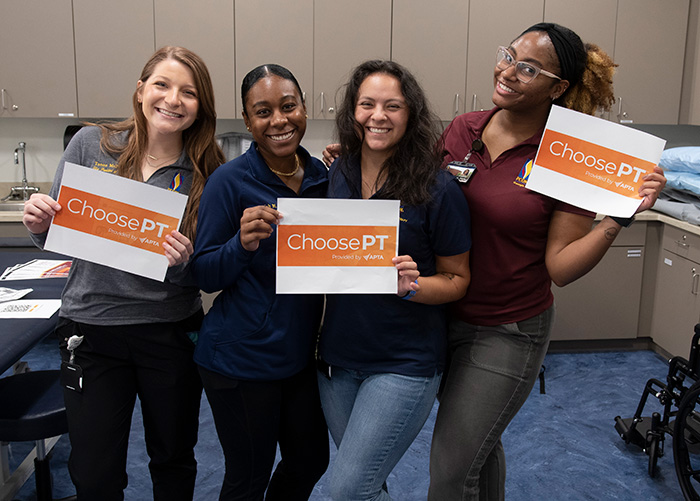 DPT students smile and hold "Choose PT" signs in a PCOM Georgia classroom.
