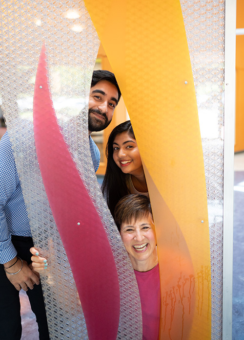 Dr. Mann and two DO students smile through the flame architecture in PCOM Georgia's main lobby.
