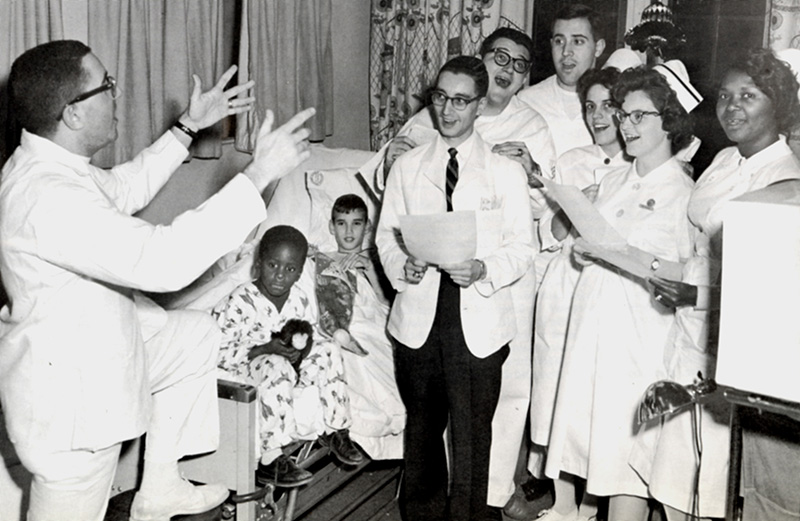 Students, physicians and staff sing during a holiday luncheon in the hospital during the 1960s.