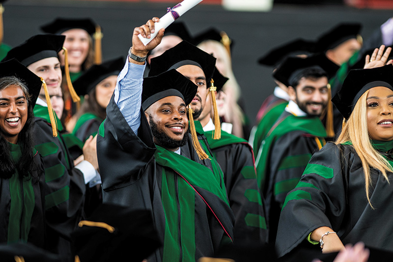 PCOM Georgia DO Class of 2022 members hold up their diplomas during their commencement ceremony.