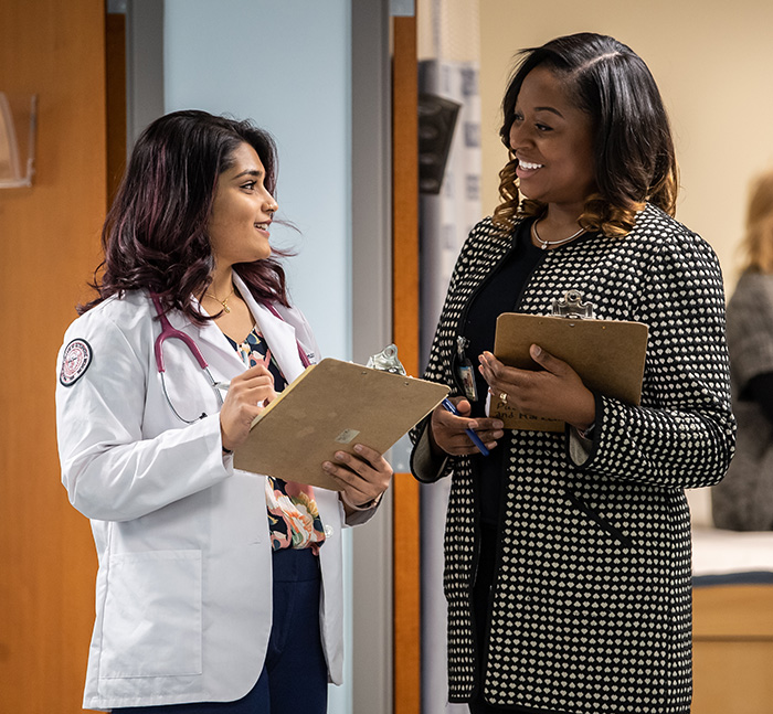 Rosmi Thomas, DO '22, and Ashley Poole, PsyD '20, discuss their notes after a simulated patient examination, 2019.