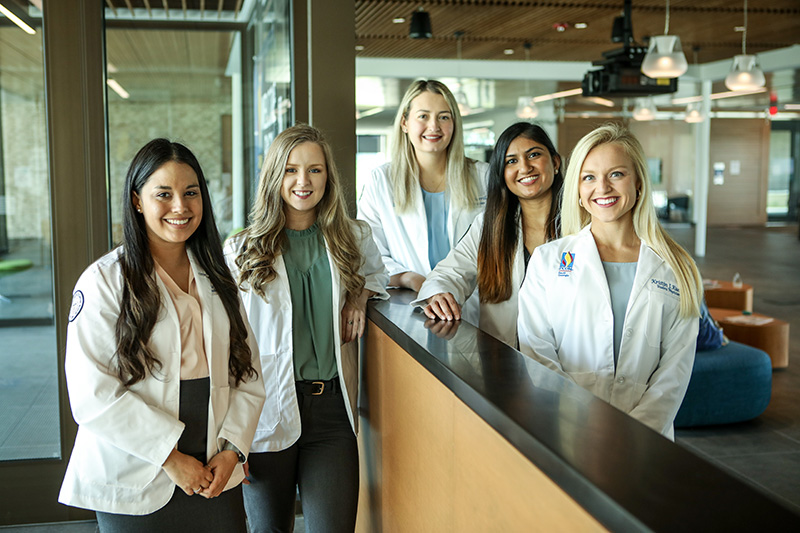 Medical students pose in their white coats in the PCOM South Georgia main lobby, 2021.