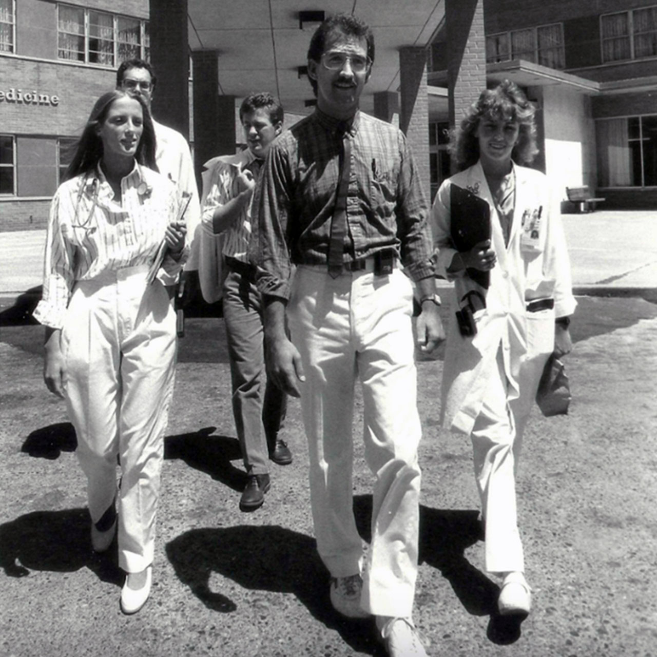 Black and white photo of PCOM residents and students walking out of the hospital building in the 1970s
