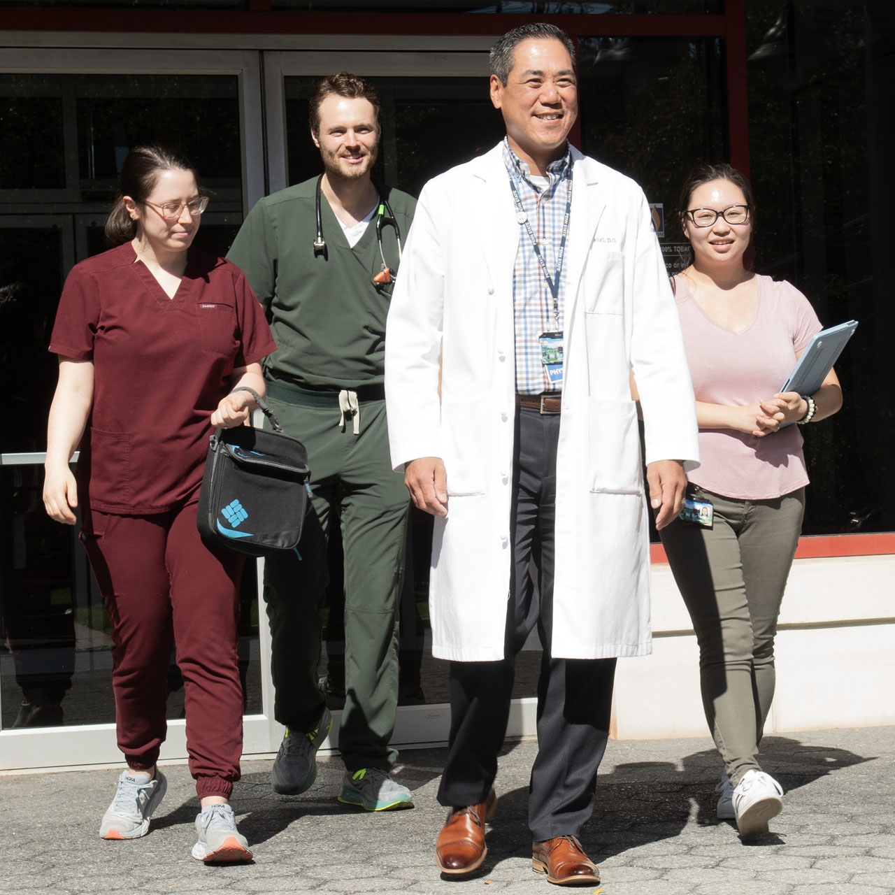 PCOM's Dr. Kuo and medical residents walk out of one of the Philadelphia campus buildings