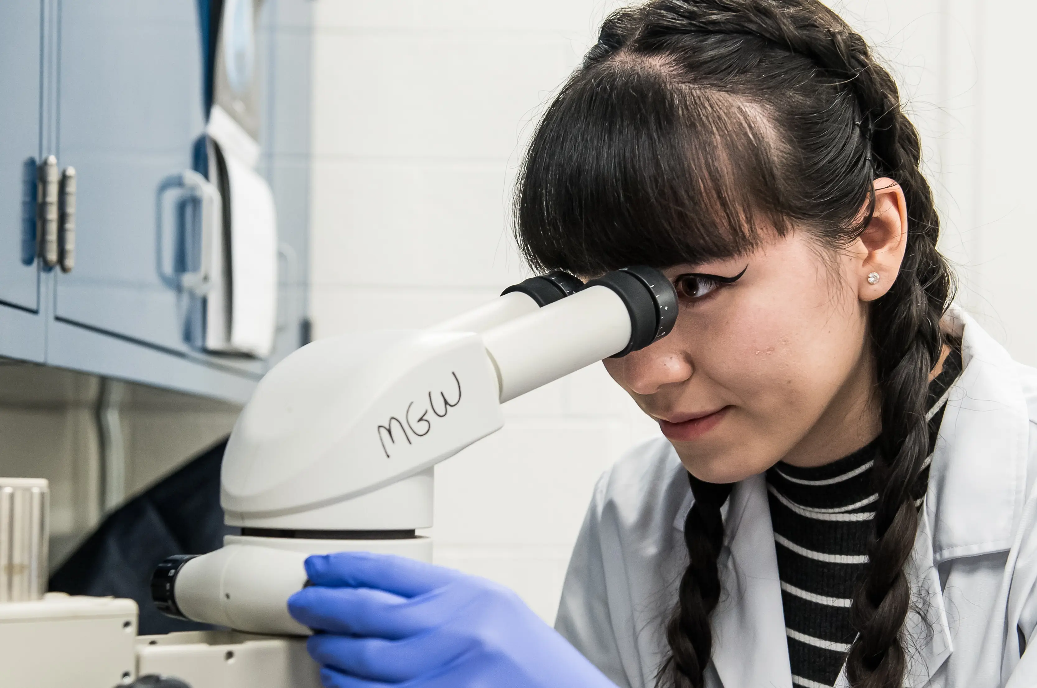 A female student looks through a microscope.