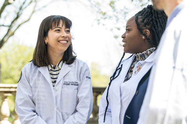 Three medical students talking outside.