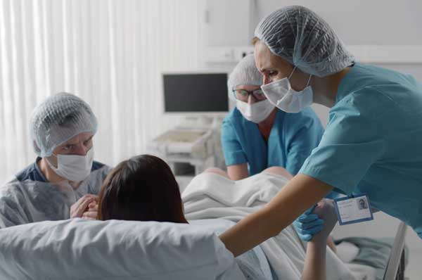 A woman is surrounded by medical staff during childbirth.
