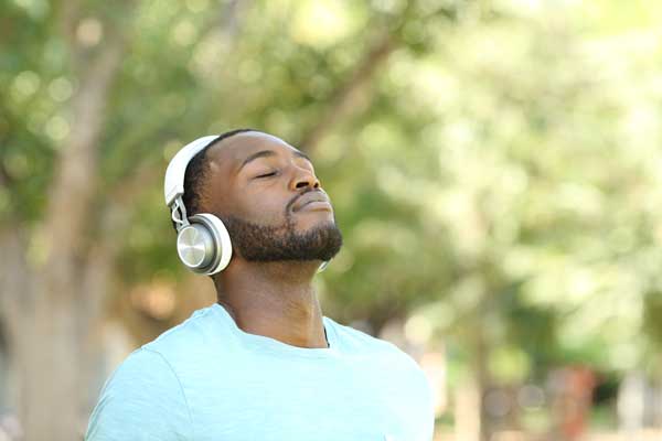 A man wearing headphones is looking upward and smiling.