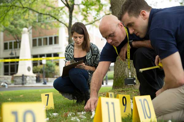 Dr. Gregory McDonald and forensic medicine students inspect a mock crime scene on PCOM's Philly campus.
