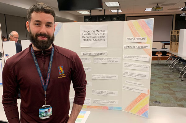 A student pursuing a degree in mental health counseling presents details of his advocacy project as part of a poster presentation.