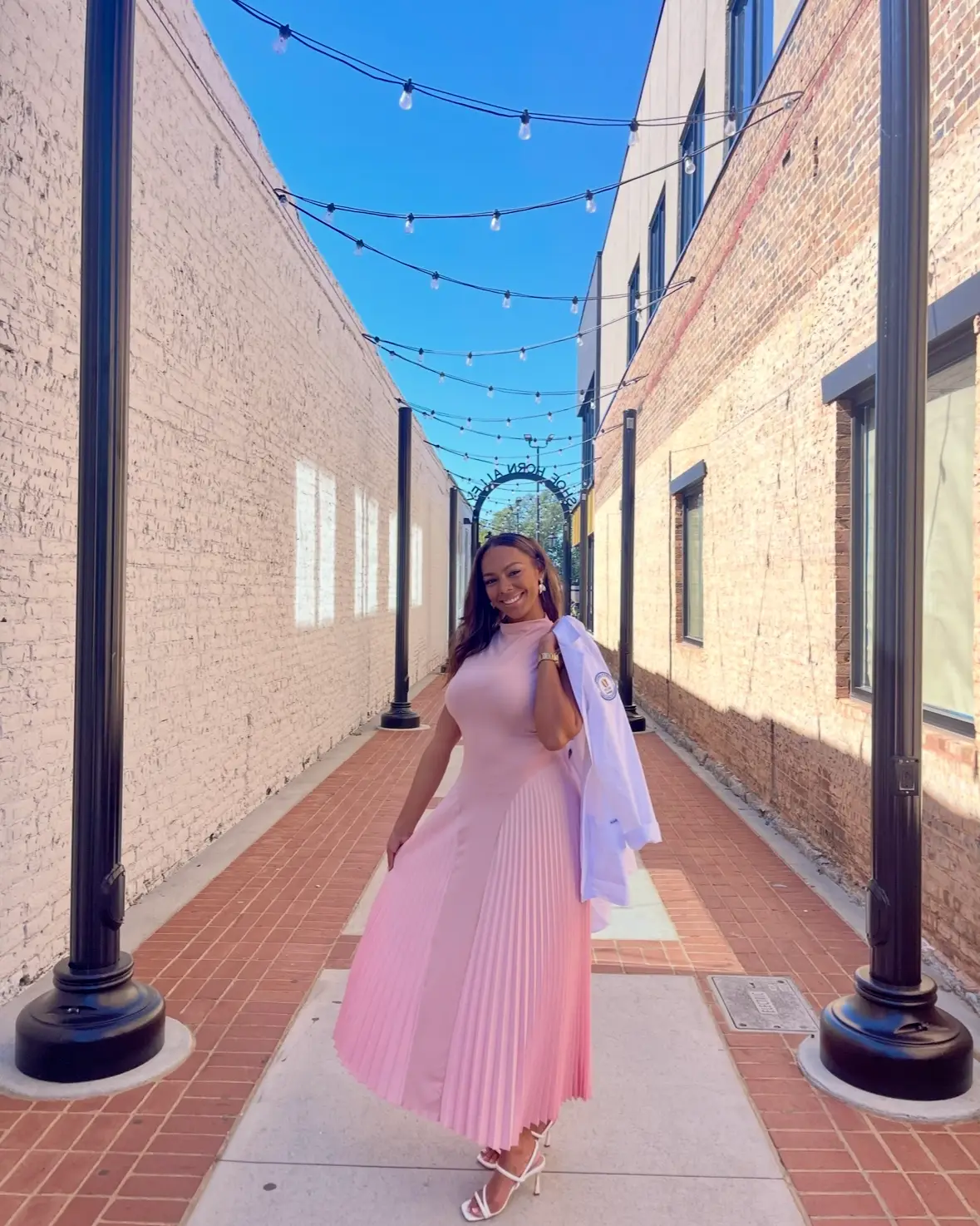Brielle White wearing a pink dress and holding her white coat.