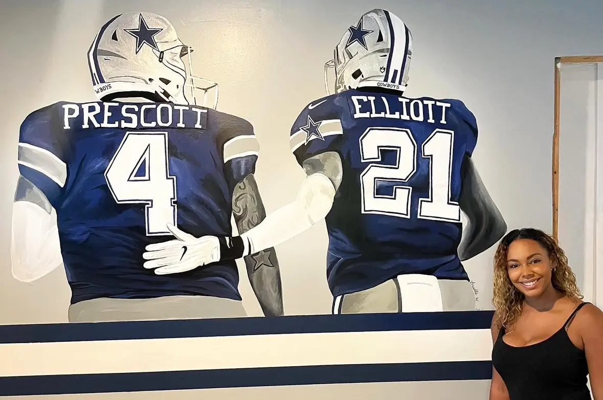Brielle White standing next to her painting of two Dallas Cowboys football players