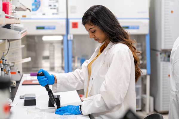 A pharmacy student is shown working inside a pharmacy research lab.
