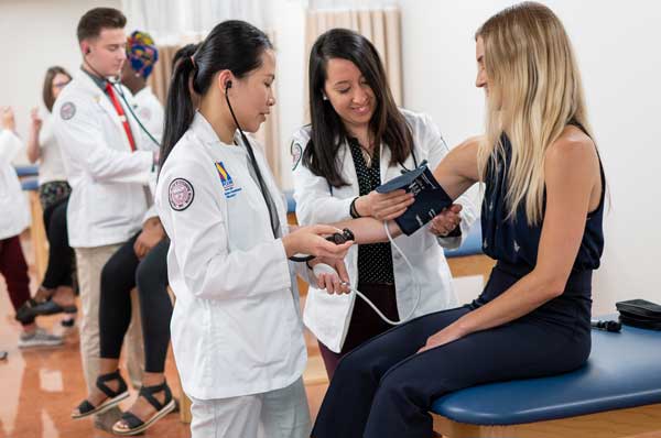 A physician assistant takes a patient's blood pressure in an examination room.