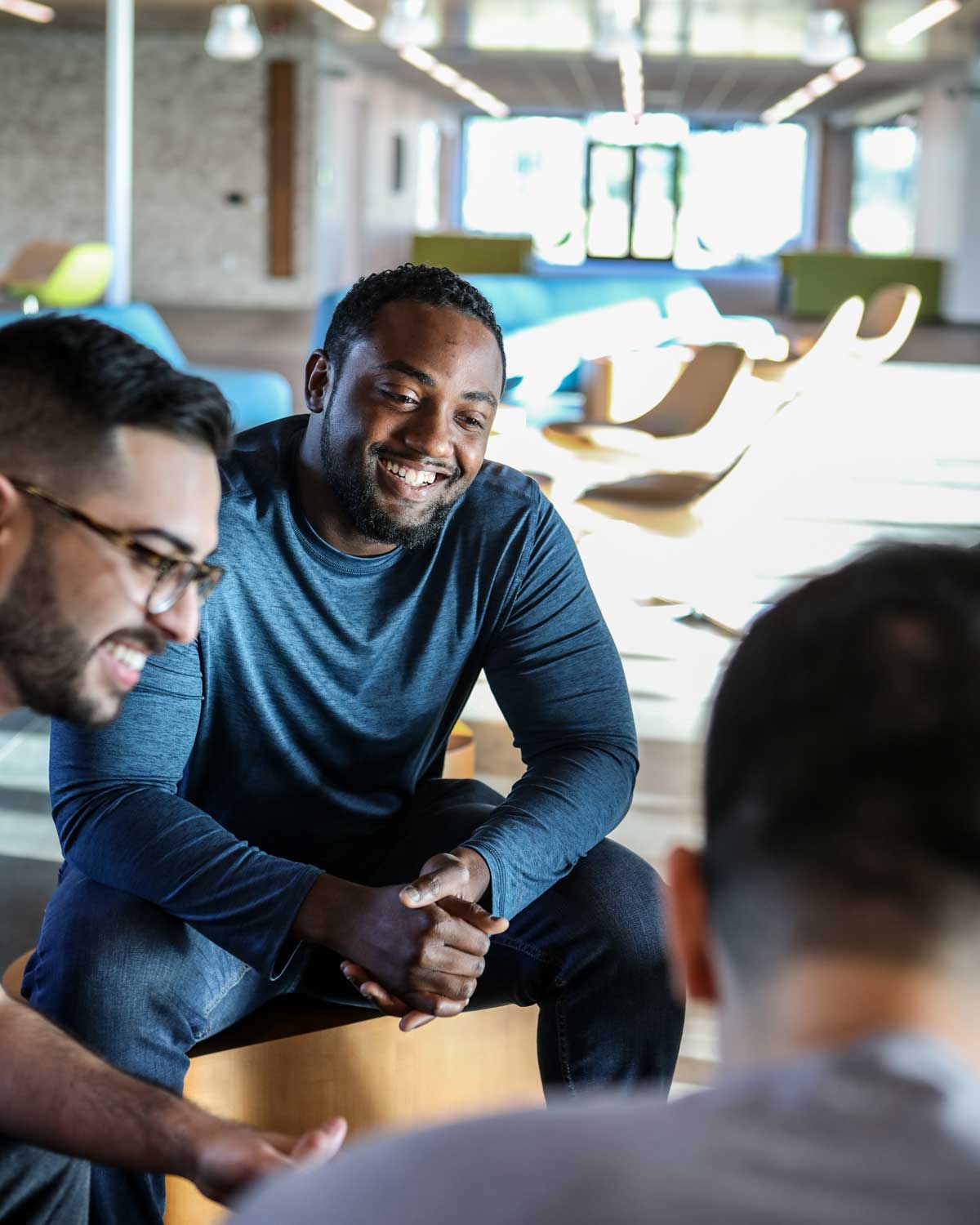 What is positive psychology? It is a discipline focused on happiness, resilence and quality of life. Here, a male student is smiling while talking with other students.