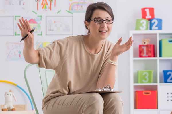 School Psychologist seated in front of a grade school class while holding clipboard