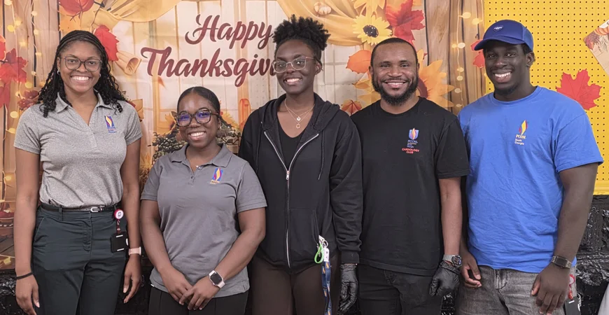Student volunteers smile in front of a "Happy Thanksgiving" banner