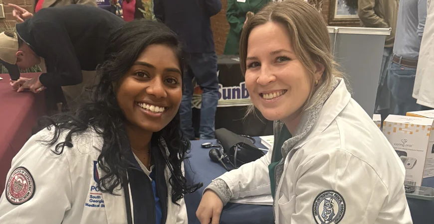 DO students in white coats smile during the Sunbelt Ag Expo