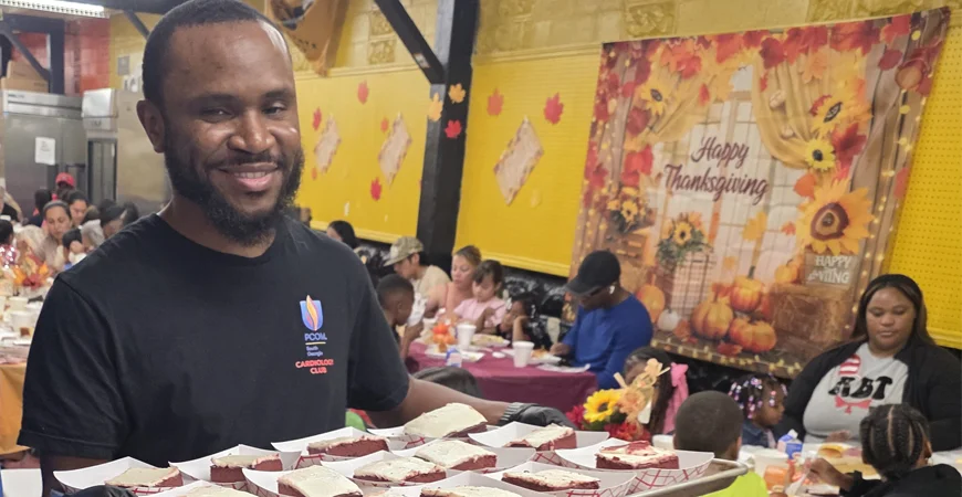 A student volunteer serves a tray of desserts during a Thanksgiving event