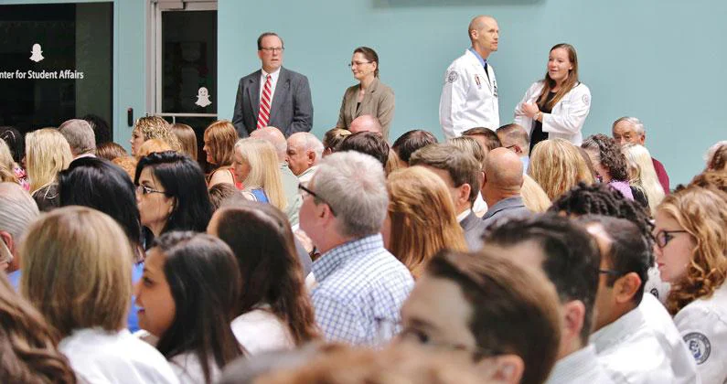 A room full of seated guests with a few PCOM Georgia faculty and students standing in the background.