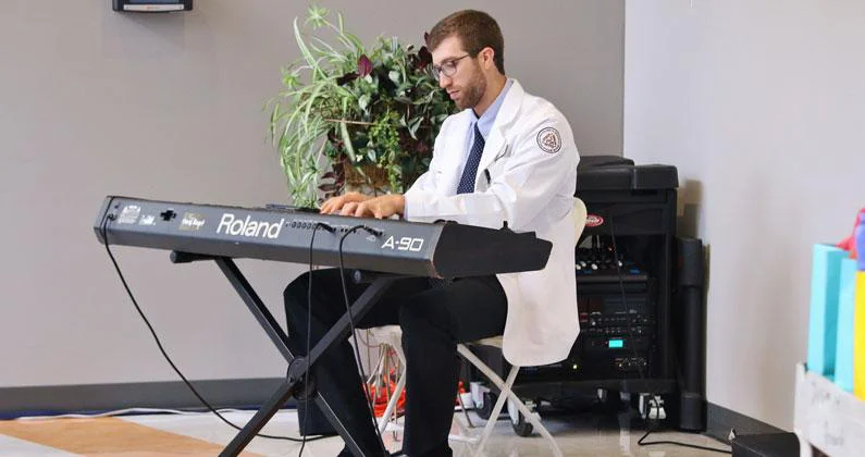 A PCOM Georgia student seated in front of an electronic keyboard.