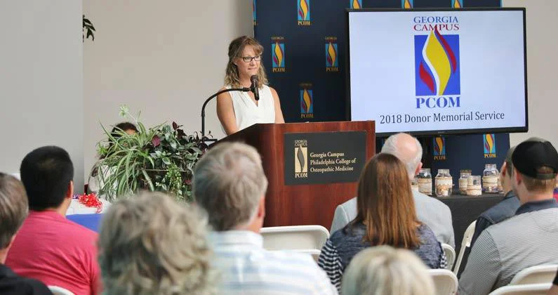 A speaker stands at a podium and addresses the seated guests. 