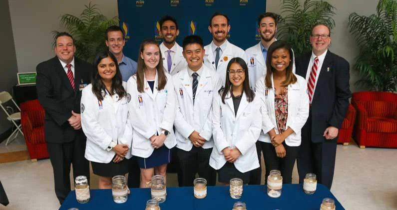 Jeff Sieple and a group of medical students in white lab coats pose for a group photo