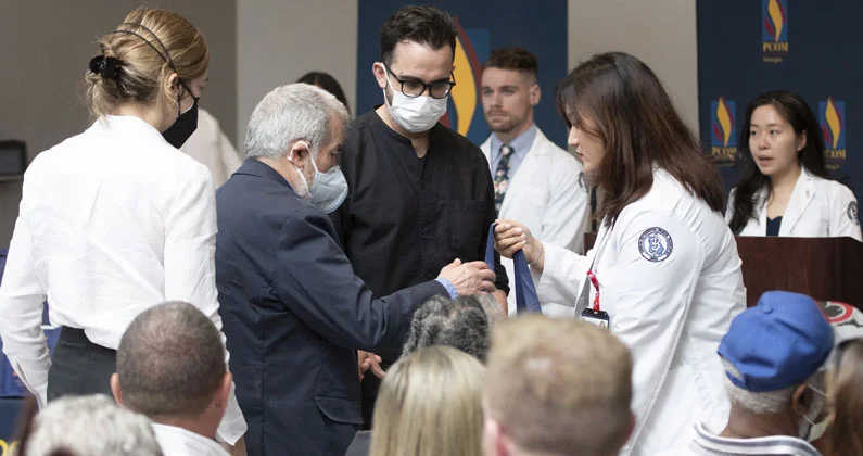 A student hands a bag to a group of audience members wearing face masks