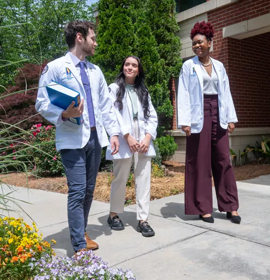 PCOM Georgia students smiling while walking and talking on a path outdoors