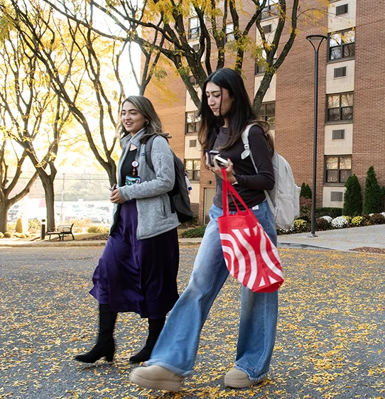 Two PCOM grad students walking and talking on a path during autumn on PCOM's Philadelphia campus