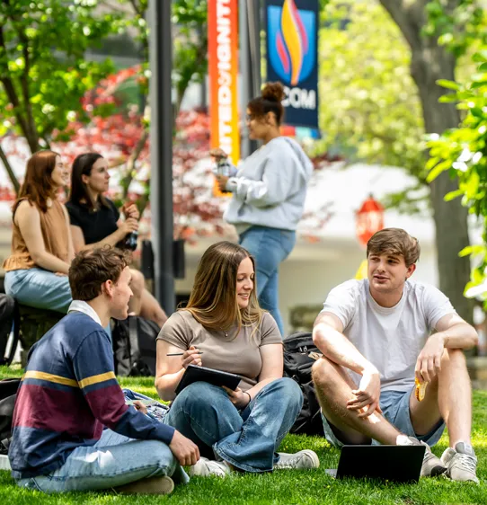 PCOM grad students sitting and talking in a grass area of PCOM's Philadelphia campus
