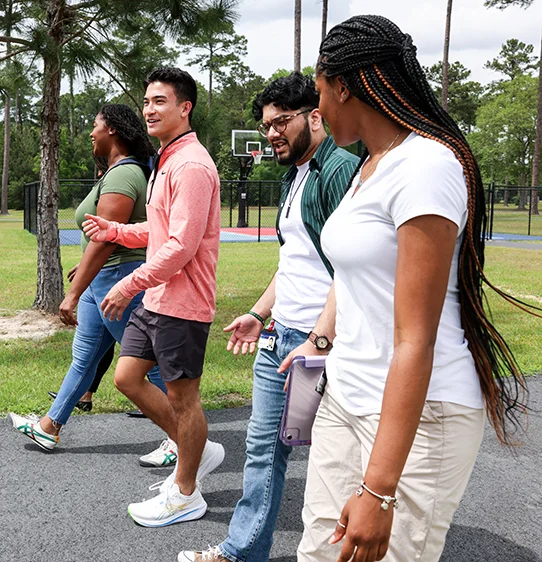 Graduate students walking and talking on a paved pathway on PCOM South Georgia's campus