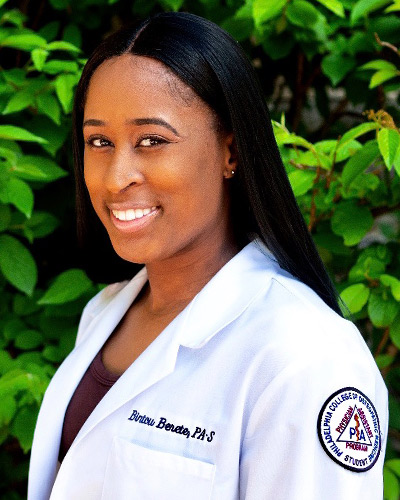 Headshot photograph of PCOM physician assistant studies gradaute Bintou Berete smiling and wearing her white coat