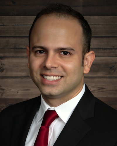 Professional headshot photograph of Efrain Padilla, DO '20, smiling and wearing a black suit.