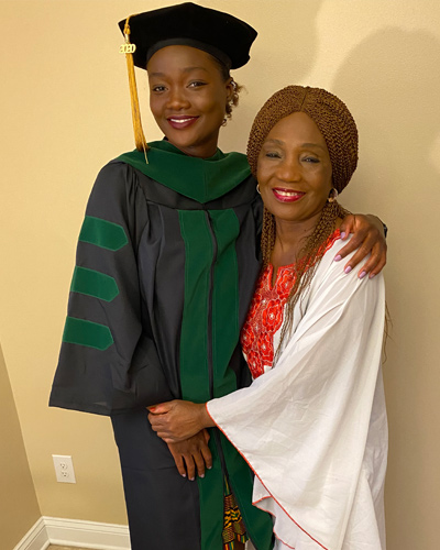 Memu-lye Kamara (Memi), DO '20, poses with her mother Isatu Sankoh in her black and green commencement regalia.