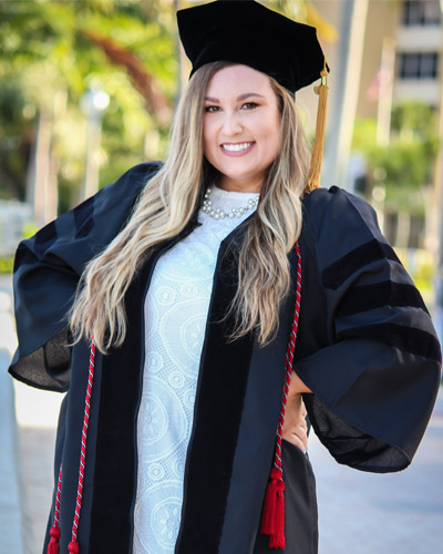 Pharmacy graduate Samantha Sabada posing in her cap and gown outdoors