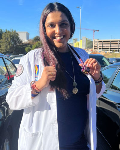 Avini Sharma, MS, poses with her white coat and stethoscope