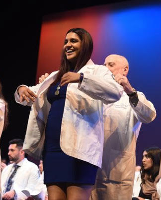 Avini Sharma, MS, receives her white coat on stage