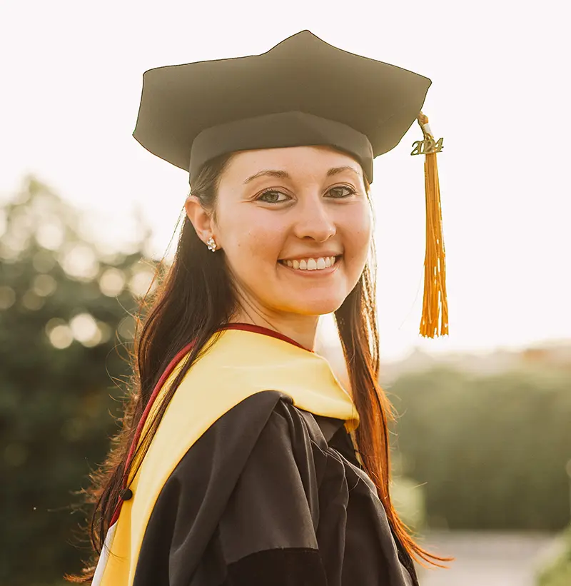 PCOM clinical psychology graduate Emily Fannick, PsyD '24, smiles in her cap and gown