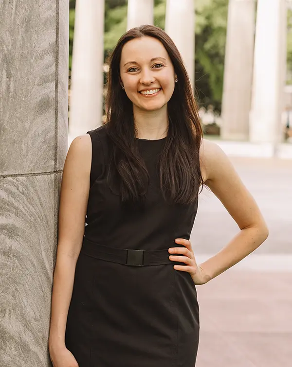 PCOM PsyD student Emily Fannick smiles and poses in dress among a sculpture garden