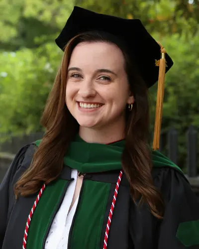 Headshot photograph of med student Macy Rowan, DO '24, smiling in her cap and gown